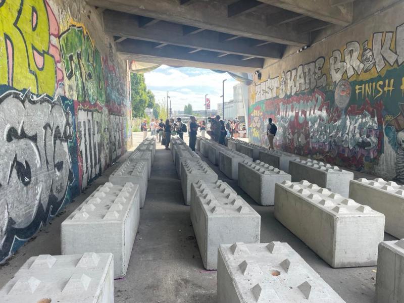 Photo of what was previously a homeless encampment beneath an underpass in Paris, France, now cleared of unhoused residents and filled with large cement blocks with anti-sitting spikes on top of them. Photo taken by Dave Zirin on July 24, 2024.