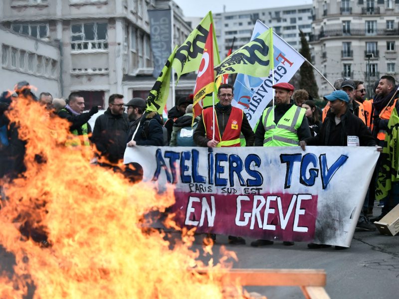 Transport workers hold a banner that reads 'Workshop TGV Paris South East on Strike' during a protest called by French trade unions in outside the Gare de Lyon, in Paris on Jan. 19, 2023.