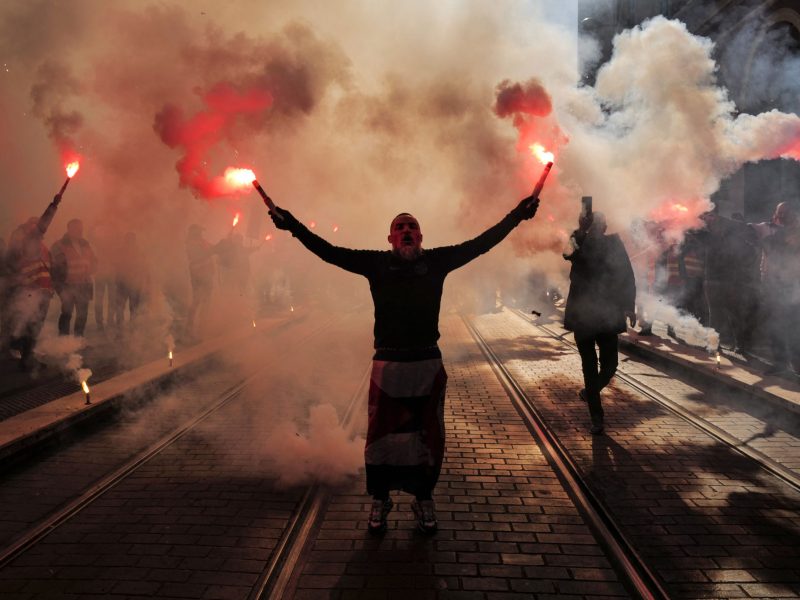 A man in the dark holding flares in each hand.