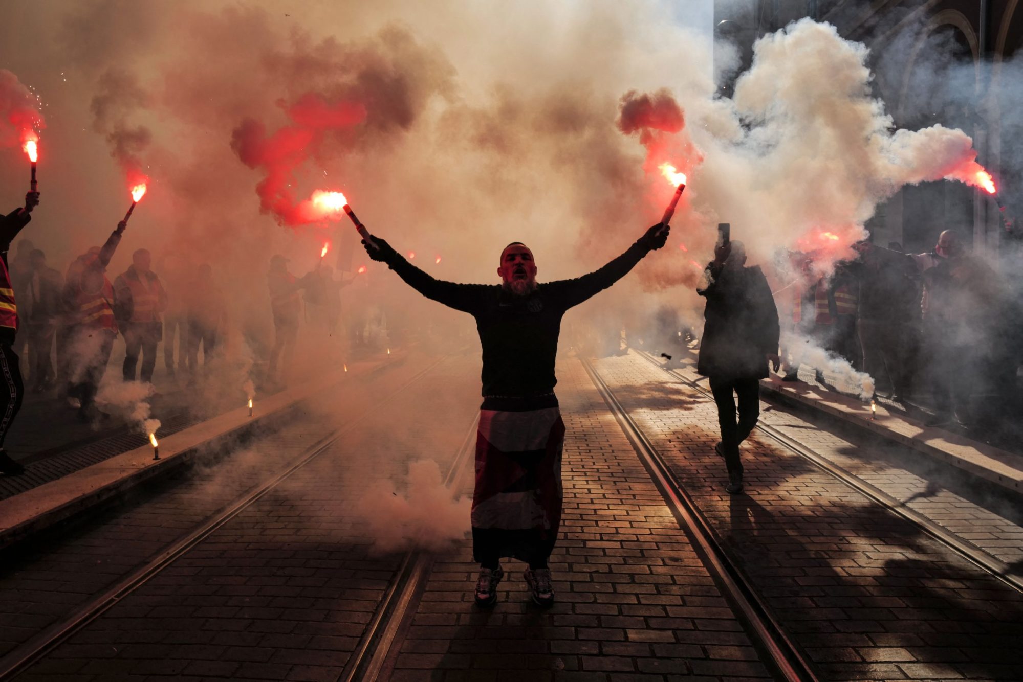 A man in the dark holding flares in each hand.