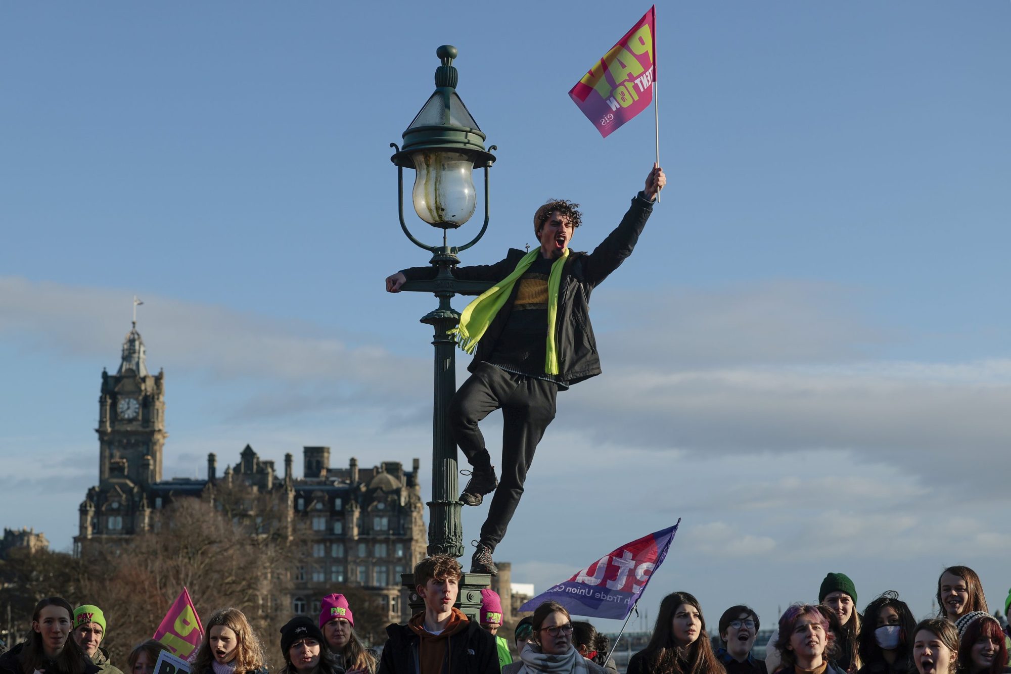 Person climbing light post holding a flag.