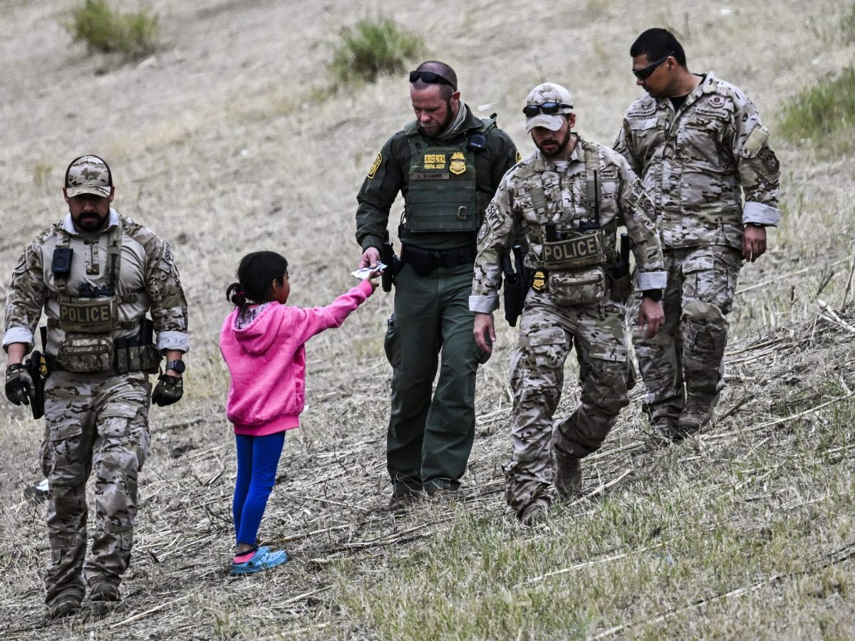 A US Customs and Border Protection officer gives food to an immigrant child waiting to be processed at a US Border Patrol transit center after crossing the border from Mexico at Eagle Pass, Texas on December 22, 2023. Photo by CHANDAN KHANNA/AFP via Getty Images