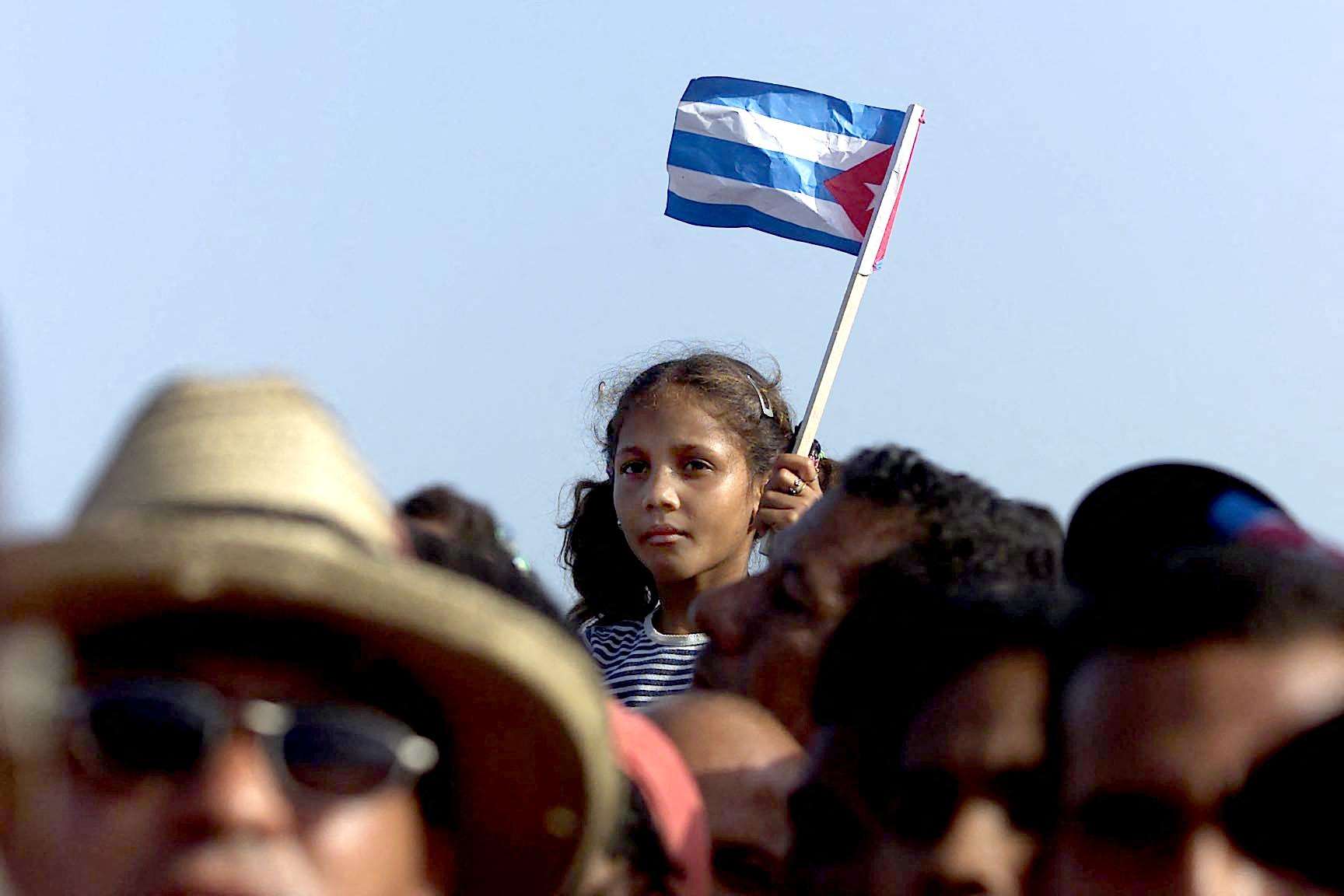 A Cuban girl wave a flag during a political meeting in the city of Manzanillo, in the province of Bayamo 01 July 2000. Photo by ADALBERTO ROQUE/AFP via Getty Images