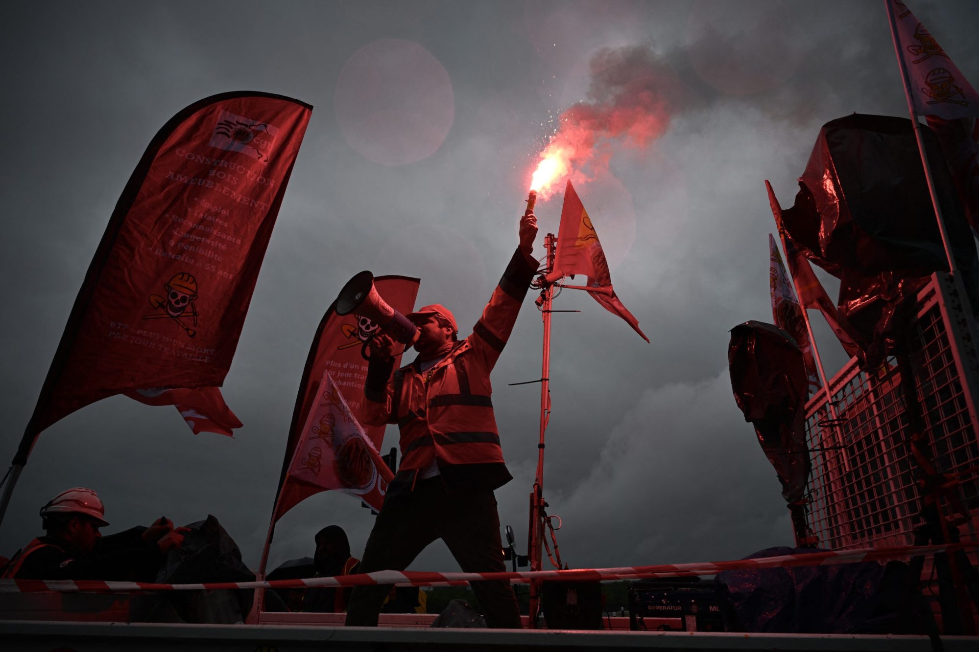 A protester on a CGT trade union truck speaks through a megaphone as he holds a burning flare during a May Day (Labour Day) rally, marking International Workers' Day, in Bordeaux, southwestern France, on May 1, 2024. Photo by PHILIPPE LOPEZ/AFP via Getty Images