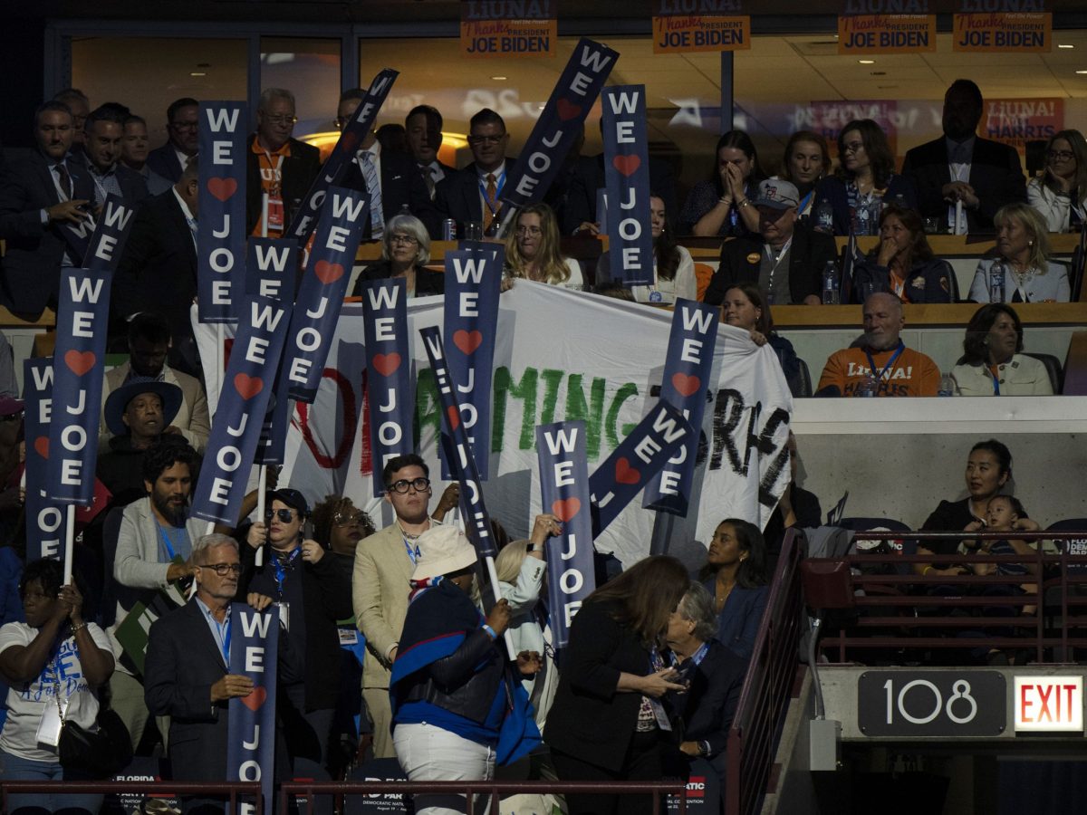 A protest banner is covered with signs in support of President Joe Biden as he delivers the keynote speech during the first day of the Democratic National Convention on August 19, 2024, at the United Center in Chicago, Illinois. Photo by Joe Lamberti for The Washington Post via Getty Images