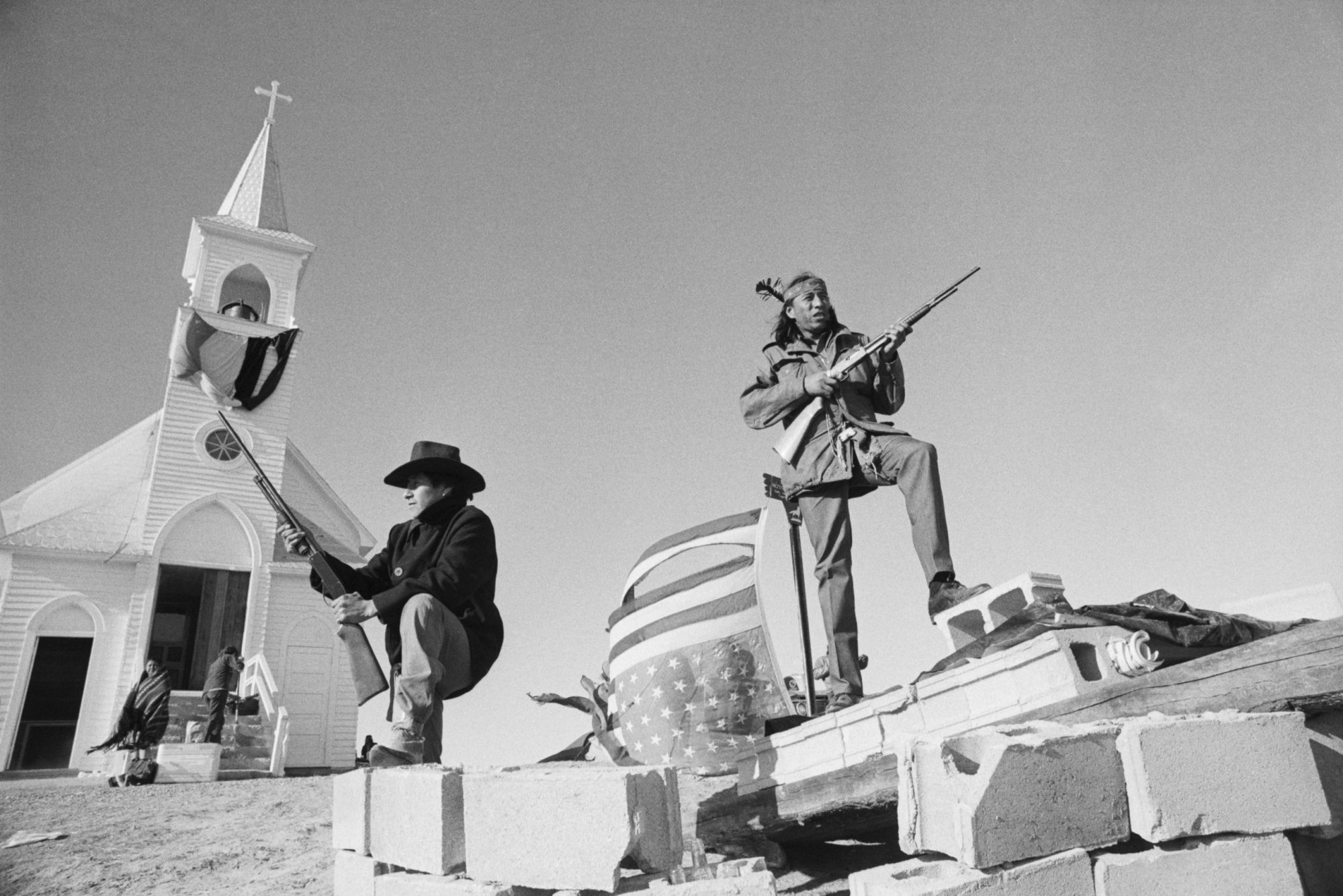 Members of the American Indian Movement and local Oglala Sioux stand guard outside the Sacred Heart Catholic Church after taking control of the town and eleven hostages during a 71 day standoff with the FBI and US Marshals.