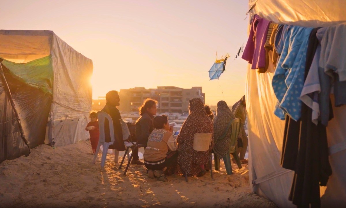 A family in Gaza shares a brief moment together at sunset outside of their tent in a makeshift refugee camp. Screenshot from video by Ruwaida Amer